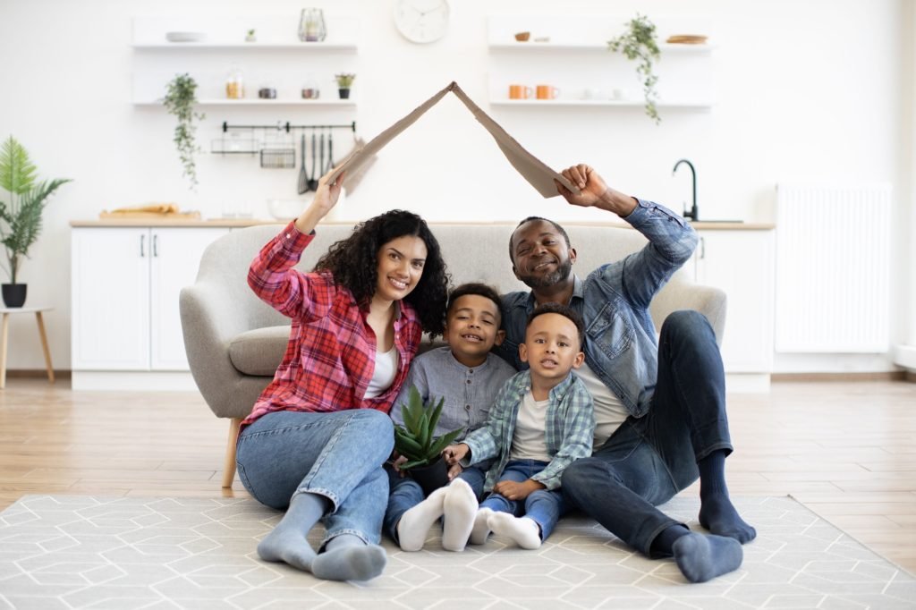 Family holding box as house roof above head on moving day