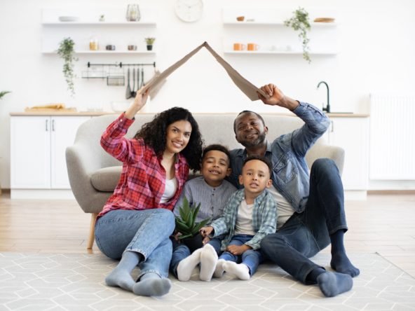 Family holding box as house roof above head on moving day