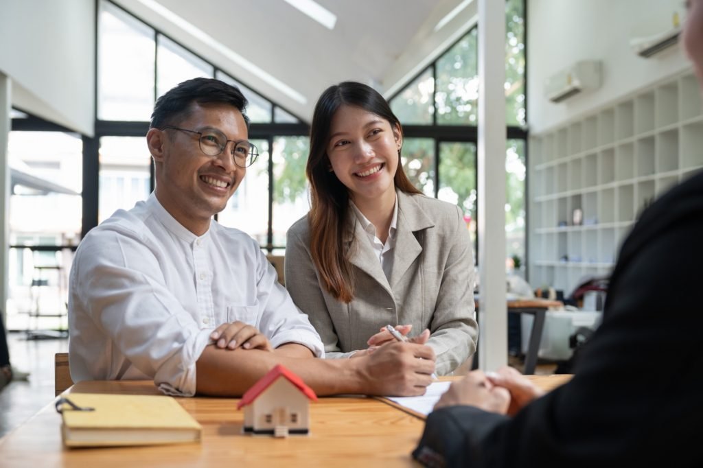 Happy property owners with real estate broker after a deal. Young couple handshaking real estate