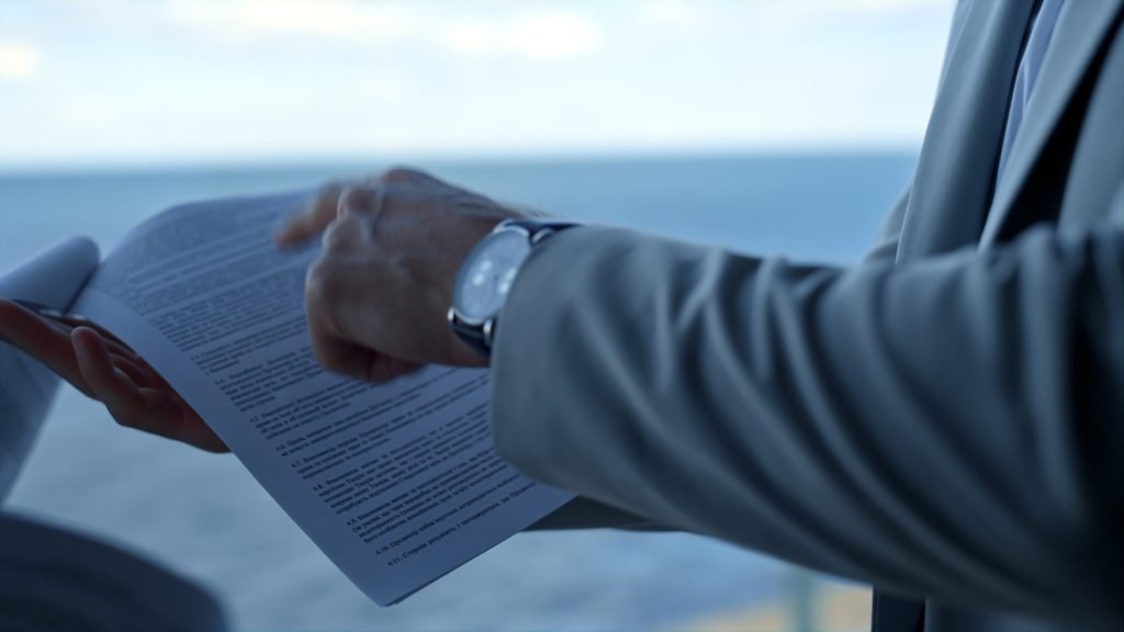 Partners discussing contract details at sea view. Closeup hand pointing papers